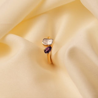 yellow gold lab grown polki diamond ring with a purple gemstone placed on a cream colored silk cloth