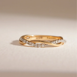 yellow gold lab grown diamond eternity band placed with a cream colored background