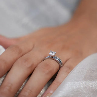 a women's hand placed on a silver surface with a white gold stackable lab grown diamond engagement ring on her ring finger