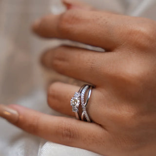 a woman's hand placed on an off-white cloth with a white gold lab grown diamond engagement ring on her ring finger 