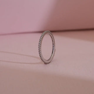 white gold lab grown diamond eternity band placed with a light pink background