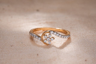 A delicate yellow gold lab-grown diamond ring from Réia Diamonds, featuring a floral cluster and a swirling pavé band.