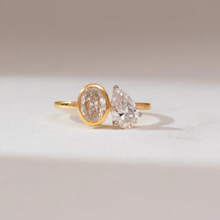 yellow gold lab grown diamond Toi et Moi placed with a white and grey background