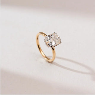 yellow gold cushion cut lab grown diamond engagement ring placed with an off white background
