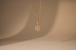Rose gold pendant featuring a flower-shaped cluster of round lab-grown diamonds, suspended from a fine chain against a warm beige backdrop.