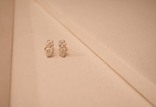 Front view of two lab-grown diamond earrings on a beige background, crafted by Réia Diamonds