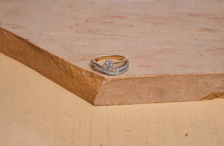 Gold ring with a floral diamond cluster design placed on a textured stone surface