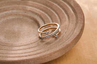 Elegant gold ring with diamond accents placed on a textured brown ceramic plate.