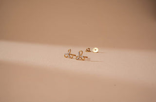 Réia lab-grown diamond stud earrings in gold with delicate design, displayed on a soft beige background for elegant minimal style.