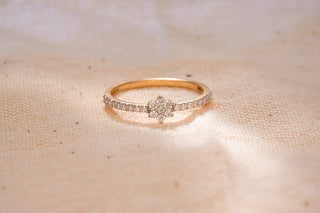 Réia lab-grown diamond ring in gold with pavé band and floral cluster design, displayed on soft beige fabric background.