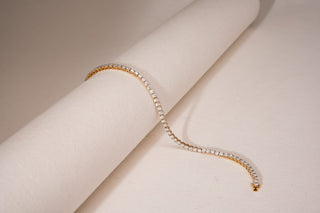 Réia lab-grown diamond bracelet in gold with a line of sparkling diamonds, elegantly draped on a soft beige textured roll.