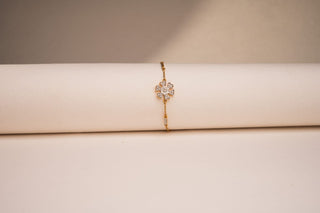 Front view of Réia gold bracelet with lab-grown diamond flower motif, displayed on beige backdrop.