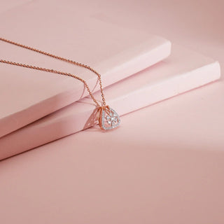 Rose gold pendant necklace with a triangular design, featuring a lab-grown diamond flower cluster and pave setting, displayed on pink risers.