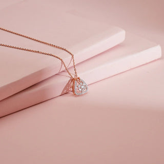 rose gold lab-grown diamond pendant placed on a light pink sheet with a light pink background