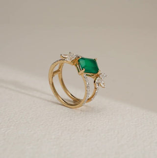 A double-band yellow gold ring with a square-cut emerald and marquise lab-grown diamonds stands on white.