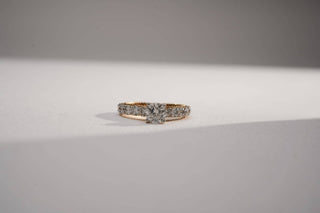 yellow gold lab-grown diamond engagement ring placed in the center of the frame with a light grey background
