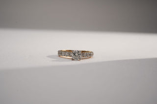 yellow gold lab-grown diamond engagement ring placed in the center of the frame with a white and grey background
