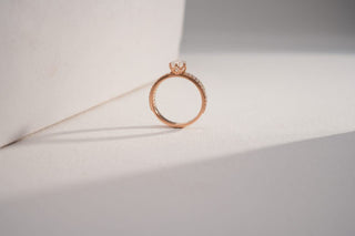 yellow gold lab-grown diamond engagement ring placed on a white surface with a white and grey background