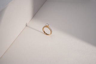 yellow gold lab-grown diamond engagement ring placed against a white sheet with a white and light grey background 