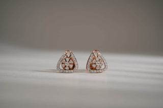 Pair of triangular rose gold stud earrings with a lab-grown diamond floral cluster center and pave halo, on a light gray surface.