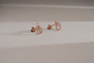 Pair of rose gold stud earrings with an oval-shaped, open setting featuring cluster-set lab-grown diamonds, resting on a white surface.
