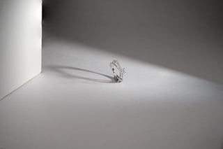 A white gold lab-grown diamond ring with a double band and pavé-set stones, featuring a princess-cut center stone, on a gray backdrop.