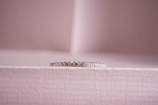 white gold lab-grown diamond engagement ring placed on a light pink surface with a blur light pink background