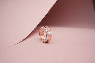 rose gold lab-grown diamond engagement ring placed beside a light pink sheet with a light pink background