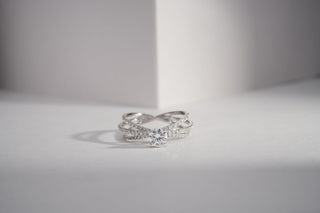 white gold lab-grown diamond engagement ring placed in front of a white sheet with a white and grey background 