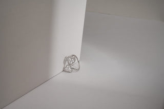 lab-grown diamond ring with a white gold band placed leaning against a white cardboard with a white and light grey background