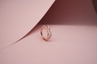 lab-grown diamond ring with a rose gold band placed beside a light pink sheet with a light pink background
