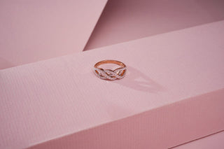 rose gold lab-grown diamond ring placed on a light pink surface with a light pink background