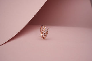 rose gold lab-grown diamond ring placed beside a light pink sheet with a light pink background