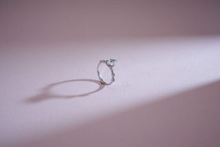white gold lab-grown diamond engagement ring placed with a light pink background