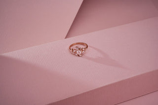 rose gold lab-grown diamond ring placed on a light pink surface with a light pink background