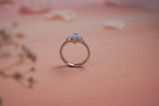 blue lab-grown coloured diamond placed amidst flower petals and baby's breath with a pink background