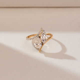 yellow gold lab grown diamond toi et moi engagement ring placed with a cream colored background