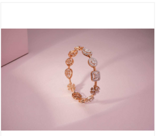 A gold bracelet featuring multiple diamond-studded charms in different shapes, displayed on a pink surface.