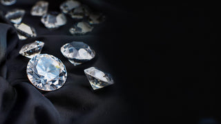 "Réia diamonds displayed on a black fabric background, showcasing various cuts of sparkling gemstones under soft lighting.