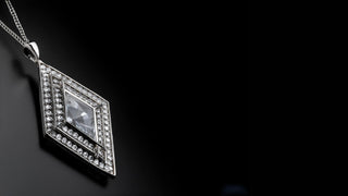 The rose gold double-circle diamond pendant from Réia Diamonds, with a solitaire in each circle, on a light grey fabric.