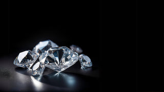 A collection of assorted loose lab-grown diamonds from Réia Diamonds, showcasing various cuts on a reflective black surface.