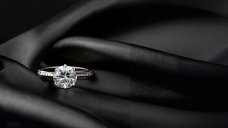 Lab-grown diamond ring by Réia Diamonds, featuring a round brilliant cut, placed on smooth black silk fabric.