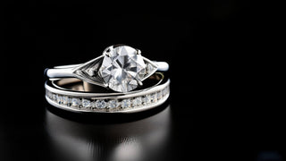Réia Diamonds lab-grown diamond bridal set featuring a solitaire engagement ring and a pavé eternity band, displayed on a sleek black surface.