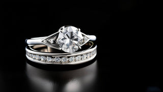 Réia Diamonds lab-grown diamond bridal set featuring a solitaire engagement ring and a pavé eternity band, displayed on a sleek black surface.