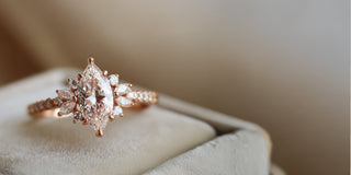 A Reia rose gold engagement ring with a large marquise lab-grown diamond, flanked by small round and marquise diamonds, set in a velvet ring box.