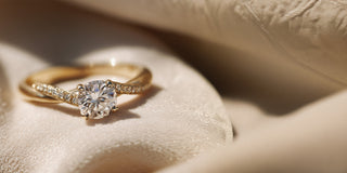 Réia yellow gold solitaire ring with a twisted lab-grown diamond band, resting on beige fabric.