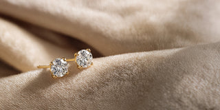 Réia yellow gold solitaire ring with a lab-grown diamond on silk fabric.