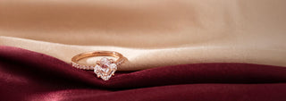 A Réia yellow gold solitaire ring featuring a large, Asscher-cut lab-grown diamond in a four-prong setting, displayed on flowing satin fabric.