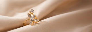 A two-tone lab-grown diamond ring features a pear-cut center stone surrounded by a halo and set on a pavé band, on wood.