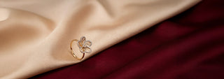 Réia rose gold diamond ring in a flower cluster design with lab-grown diamonds, displayed on beige fabric.